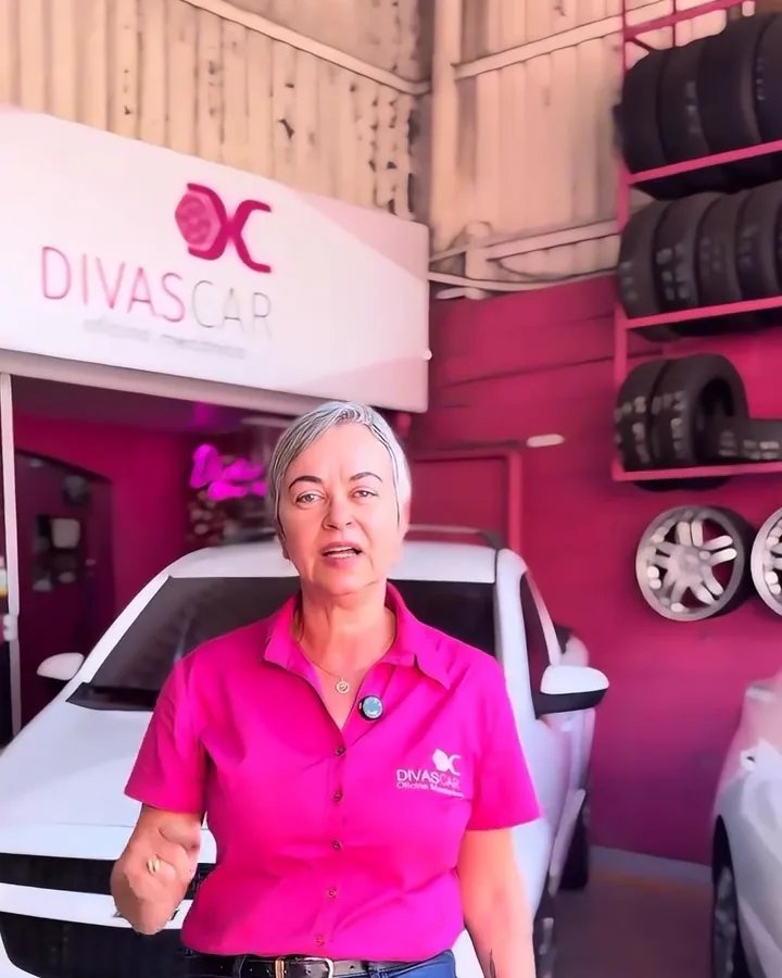 A Joelma, dona da Divas Car, embaixo do letreiro da oficina